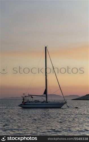 Sail boat yacht on a tranquil calm sea at sunset or sunrise in the Adriatic Sea between the Islands of Hvar and Vis, Croatia