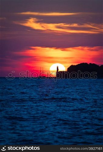 Sailboat and lighthouse on dramatic sunset in Zadar, Dalmatia, Croatia
