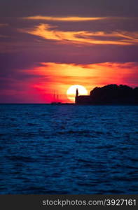 Sailboat and lighthouse on dramatic sunset in Zadar, Dalmatia, Croatia