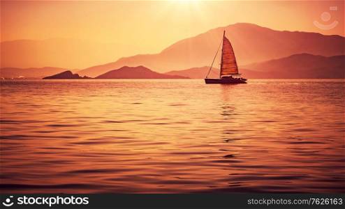 Sailboat in beautiful mild orange sunset light, sail race in Mediterranean sea, summer vacation in Turkey