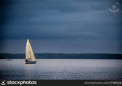 Sailboat in the sea in the afternoon light on a background of blue sky and mountains in a calm sea