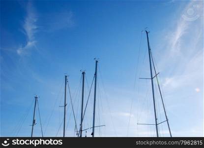 Sailboat masts in a row at blue sky with space