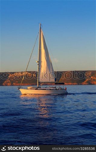 Sailboat sailing golden sunrise in blue ocean sea