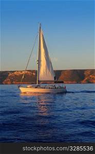 Sailboat sailing golden sunrise in blue ocean sea