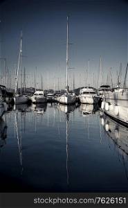 Sailboats moored in the harbor, beautiful reflection of a big long masts on the water, summer holidays on Mediterranean sea, Marmaris, Turkey