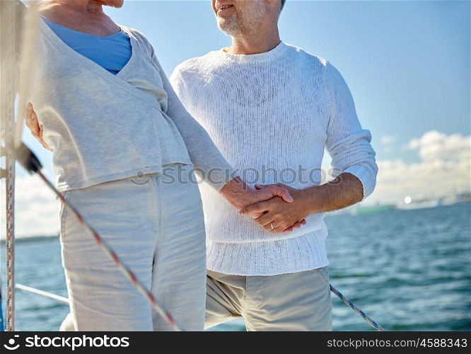 sailing, age, tourism, travel and people concept - close up of happy senior couple holding hands on sail boat or yacht deck floating in sea