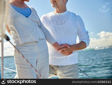 sailing, age, tourism, travel and people concept - close up of happy senior couple holding hands on sail boat or yacht deck floating in sea