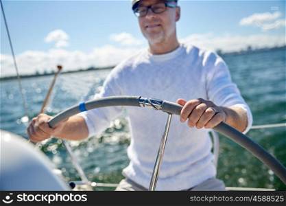 sailing, age, tourism, travel and people concept - close up of happy senior man in captain hat steering wheel and navigating sail boat or yacht floating in sea