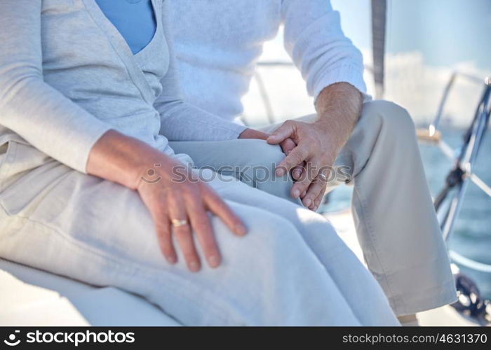 sailing, age, tourism, travel and people concept - close up of happy senior couple hugging and talking on sail boat or yacht deck floating in sea