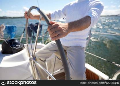 sailing, age, tourism, travel and people concept - close up of senior man steering wheel and navigating sail boat or yacht floating in sea