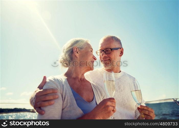sailing, age, tourism, travel and people concept - happy senior couple drinking champagne on sail boat or yacht deck floating in sea