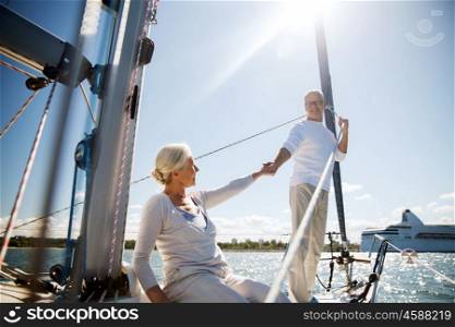 sailing, age, tourism, travel and people concept - happy senior couple holding hands on sail boat or yacht deck floating in sea