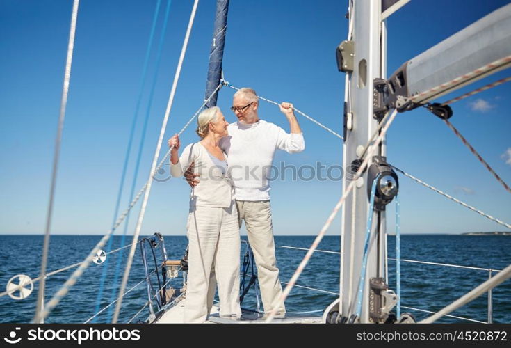 sailing, age, tourism, travel and people concept - happy senior couple hugging and talking on sail boat or yacht deck floating in sea