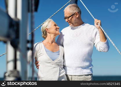 sailing, age, tourism, travel and people concept - happy senior couple hugging on sail boat or yacht deck floating in sea