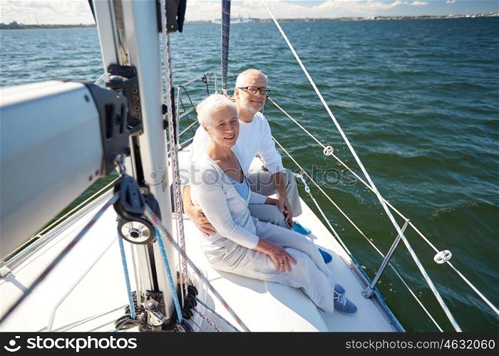sailing, age, tourism, travel and people concept - happy senior couple hugging on sail boat or yacht deck floating in sea
