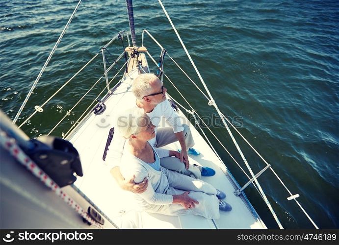 sailing, age, tourism, travel and people concept - happy senior couple hugging on sail boat or yacht deck floating in sea