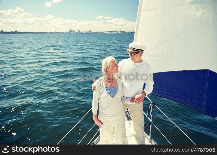 sailing, age, tourism, travel and people concept - happy senior couple hugging and talking on sail boat or yacht deck floating in sea