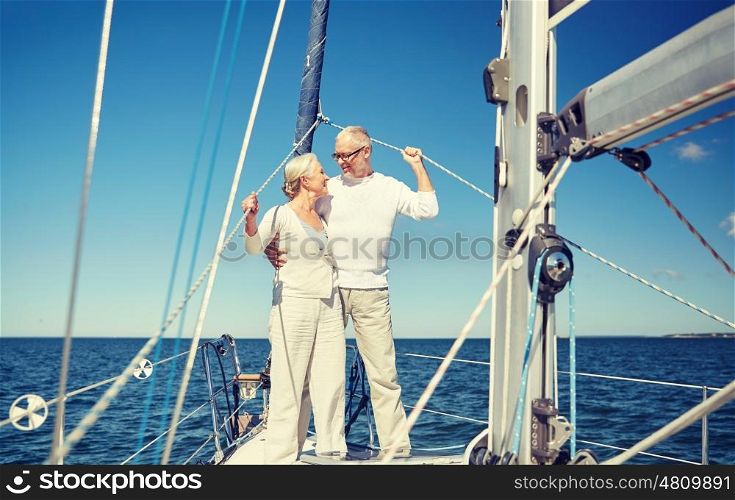 sailing, age, tourism, travel and people concept - happy senior couple hugging and talking on sail boat or yacht deck floating in sea. senior couple hugging on sail boat or yacht in sea