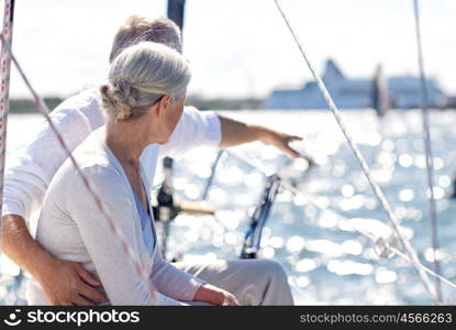 sailing, age, tourism, travel and people concept - happy senior couple pointing finger on sail boat or yacht deck floating in sea