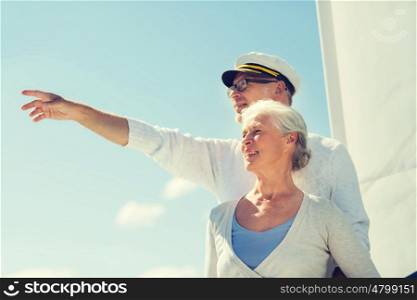 sailing, age, tourism, travel and people concept - happy senior couple pointing finger on sail boat or yacht deck floating in sea