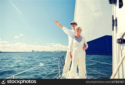 sailing, age, tourism, travel and people concept - happy senior couple pointing finger to something on sail boat or yacht deck floating in sea