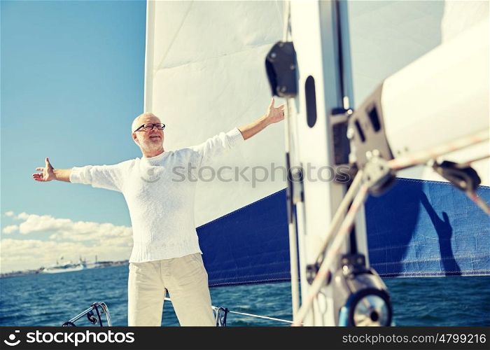 sailing, age, tourism, travel and people concept - happy senior man enjoying freedom on sail boat or yacht floating in sea