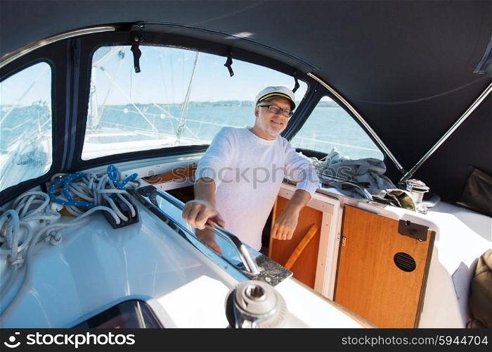 sailing, age, tourism, travel and people concept - happy senior man in captain hat on sail boat or yacht floating in sea