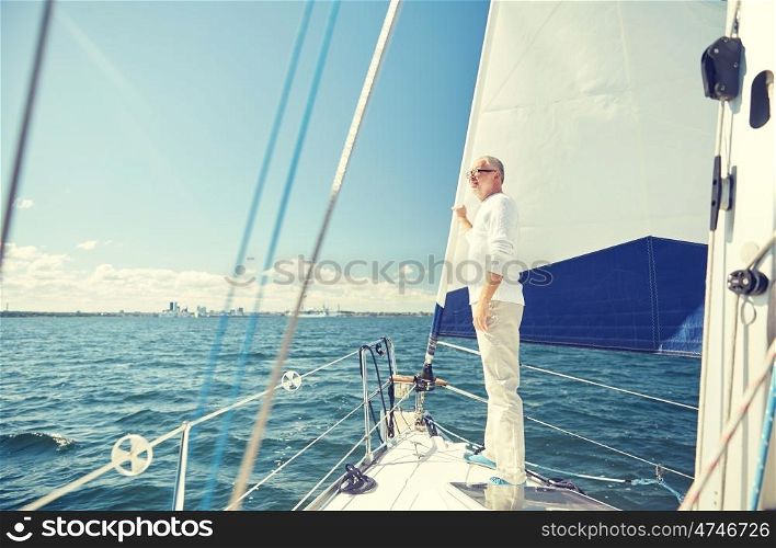 sailing, age, tourism, travel and people concept - happy senior man on sail boat or yacht floating in sea