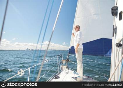 sailing, age, tourism, travel and people concept - happy senior man on sail boat or yacht floating in sea