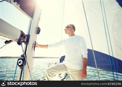 sailing, age, tourism, travel and people concept - senior man on sail boat or yacht floating in sea