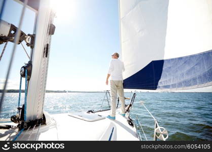 sailing, age, tourism, travel and people concept - senior man on sail boat or yacht floating in sea