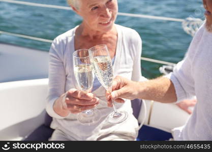 sailing, age, travel, holidays and people concept - close up of happy senior couple drinking champagne on sail boat or yacht deck floating in sea