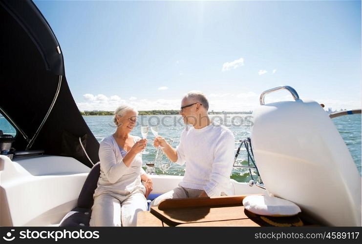 sailing, age, travel, holidays and people concept - happy senior couple clinking champagne glasses on sail boat or yacht deck floating in sea