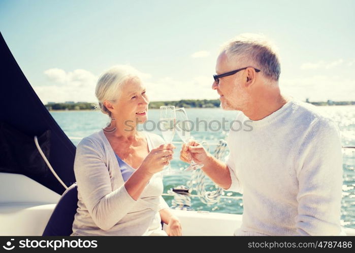 sailing, age, travel, holidays and people concept - happy senior couple clinking champagne glasses on sail boat or yacht deck floating in sea