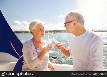 sailing, age, travel, holidays and people concept - happy senior couple clinking champagne glasses on sail boat or yacht deck floating in sea