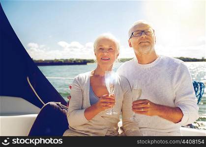 sailing, age, travel, holidays and people concept - happy senior couple with champagne glasses on sail boat or yacht deck floating in sea
