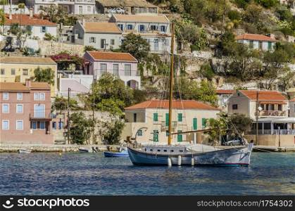 sailing boat moored in the waters of the bay of assos harbor of the same name dock and houses surrounding it on the island of kefalonia