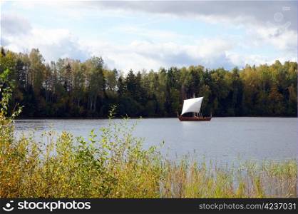 Sailing boat on a background of a forest and the sky
