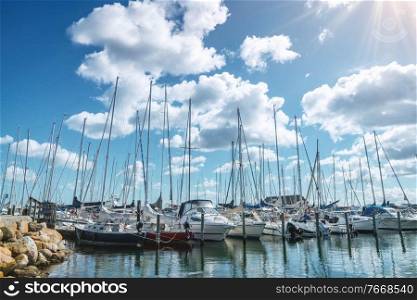 Sailing boats in a marine harbor in the summer with the sun shining from a blue sky