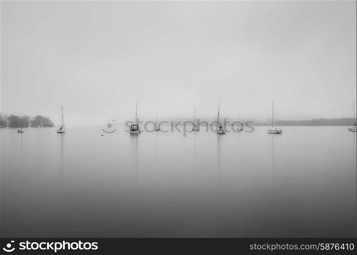 Sailing boats in fog on Lake Windermere in Lake District in black and white