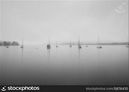 Sailing boats in fog on Lake Windermere in Lake District in black and white