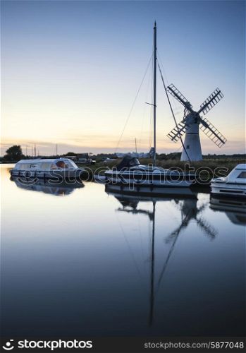 Sailing boats moored on riverbank at sunrise in countryside landscape