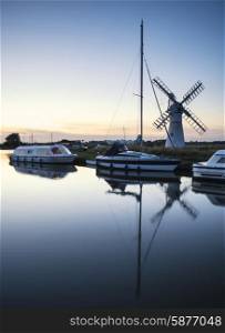 Sailing boats moored on riverbank at sunrise in countryside landscape