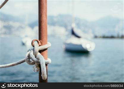 Sailing rope on a wooden dock pier in the foreground, sailing boats in the blurry background