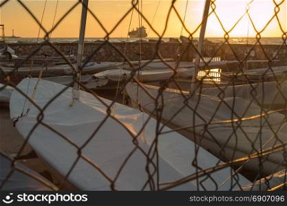 Sailing Ships in Small Port and Supply Ship in background: View behind Mesh Fence