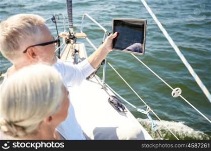 sailing, technology, tourism, travel and people concept - close up of senior couple with tablet pc computer on sail boat or yacht deck floating in sea