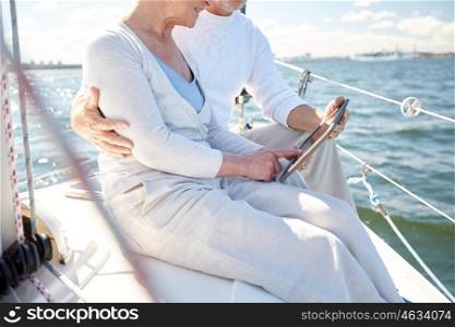 sailing, technology, tourism, travel and people concept - close up of senior couple with tablet pc computer on sail boat or yacht deck floating in sea