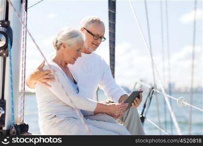 sailing, technology, tourism, travel and people concept - happy senior couple with tablet pc computer on sail boat or yacht deck floating in sea