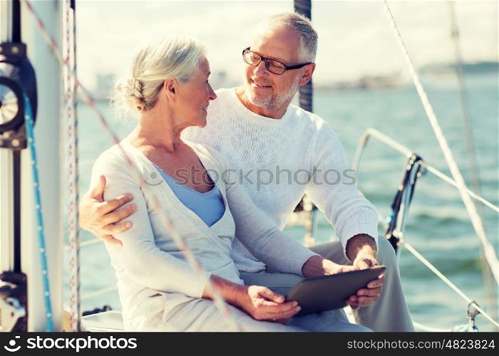 sailing, technology, tourism, travel and people concept - happy senior couple with tablet pc computer on sail boat or yacht deck floating in sea