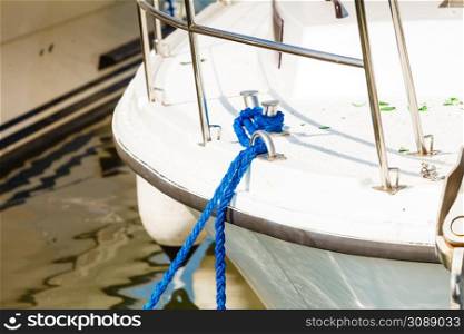 Sailing, yachting, security concept. Tied blue sailing rope on white boat, outdoor shot. Tied blue sailing rope on white boat